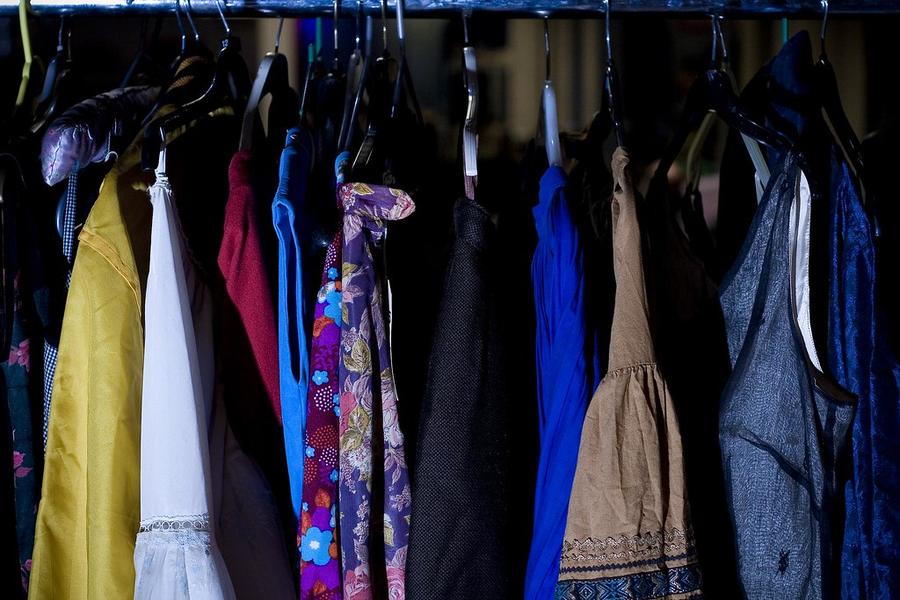 Racks of vintage dresses and shirts on wooden hangers