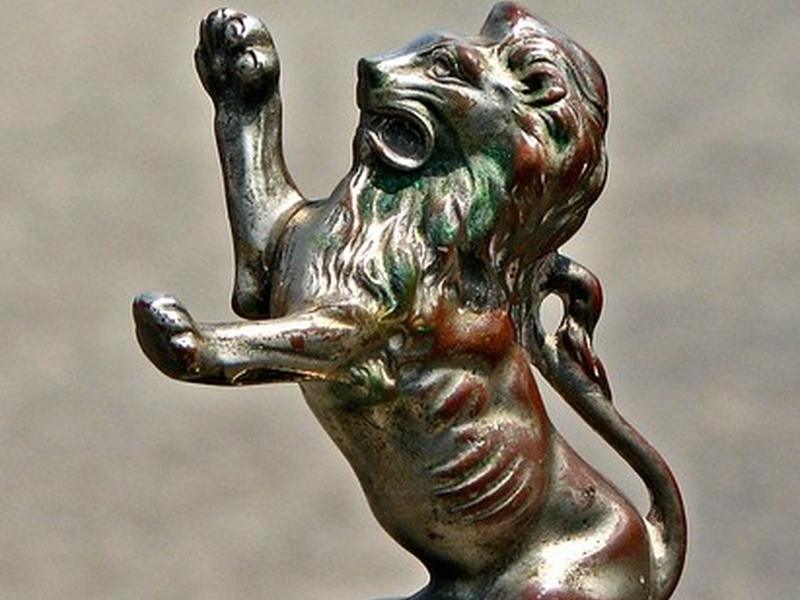 A brass lion hood ornament, mid-roar