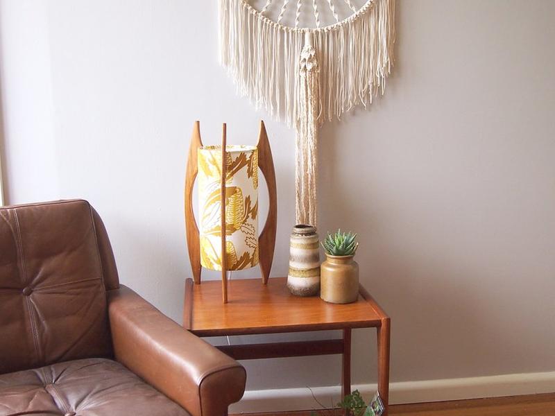 A giant circular macramé wall hanging above a leather armchair