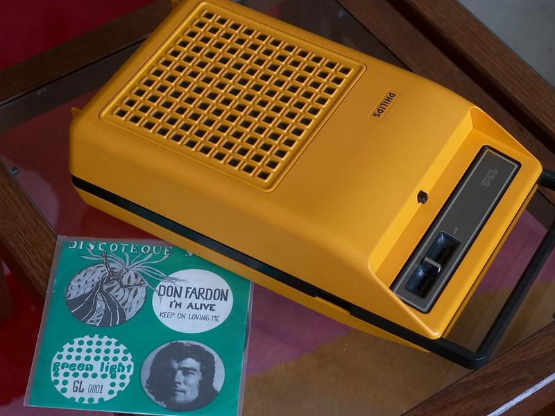 A bright yellow Philips portable record player with 45s