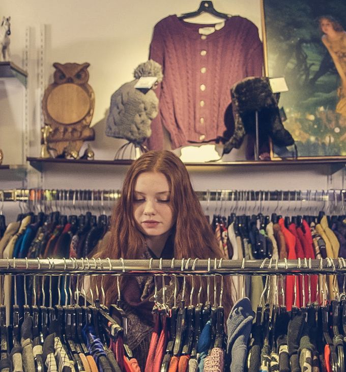 A shopper browsing a packed rack of vintage clothes inside the shop