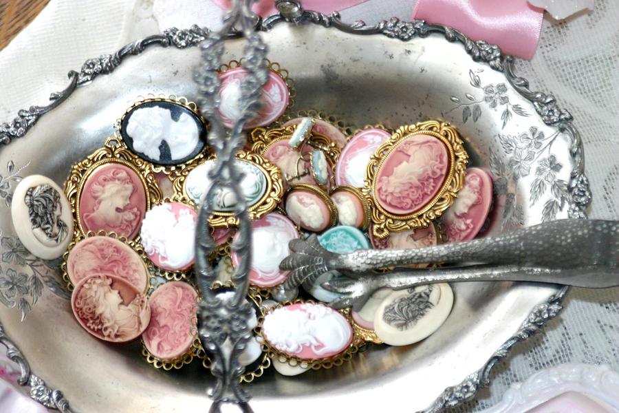 A silver tray piled with vintage cameo brooches